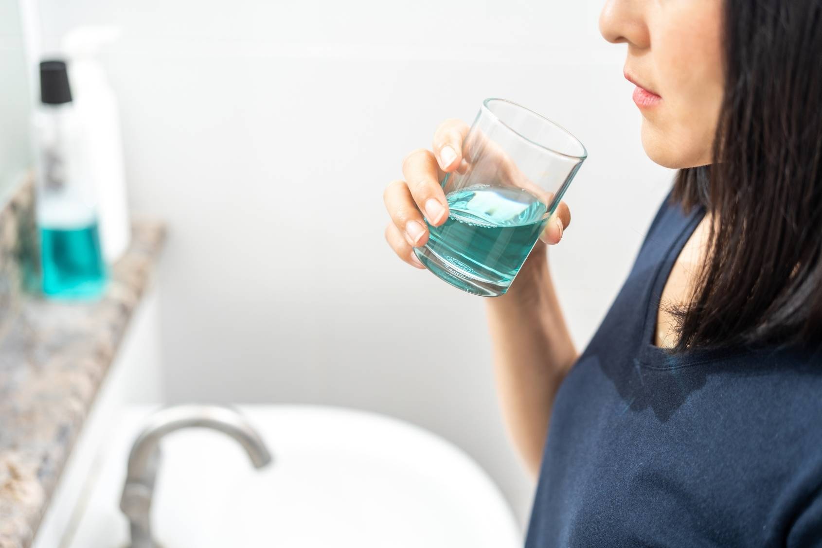 Mevrouw met mondwater of mondspoelmiddel in een glas.